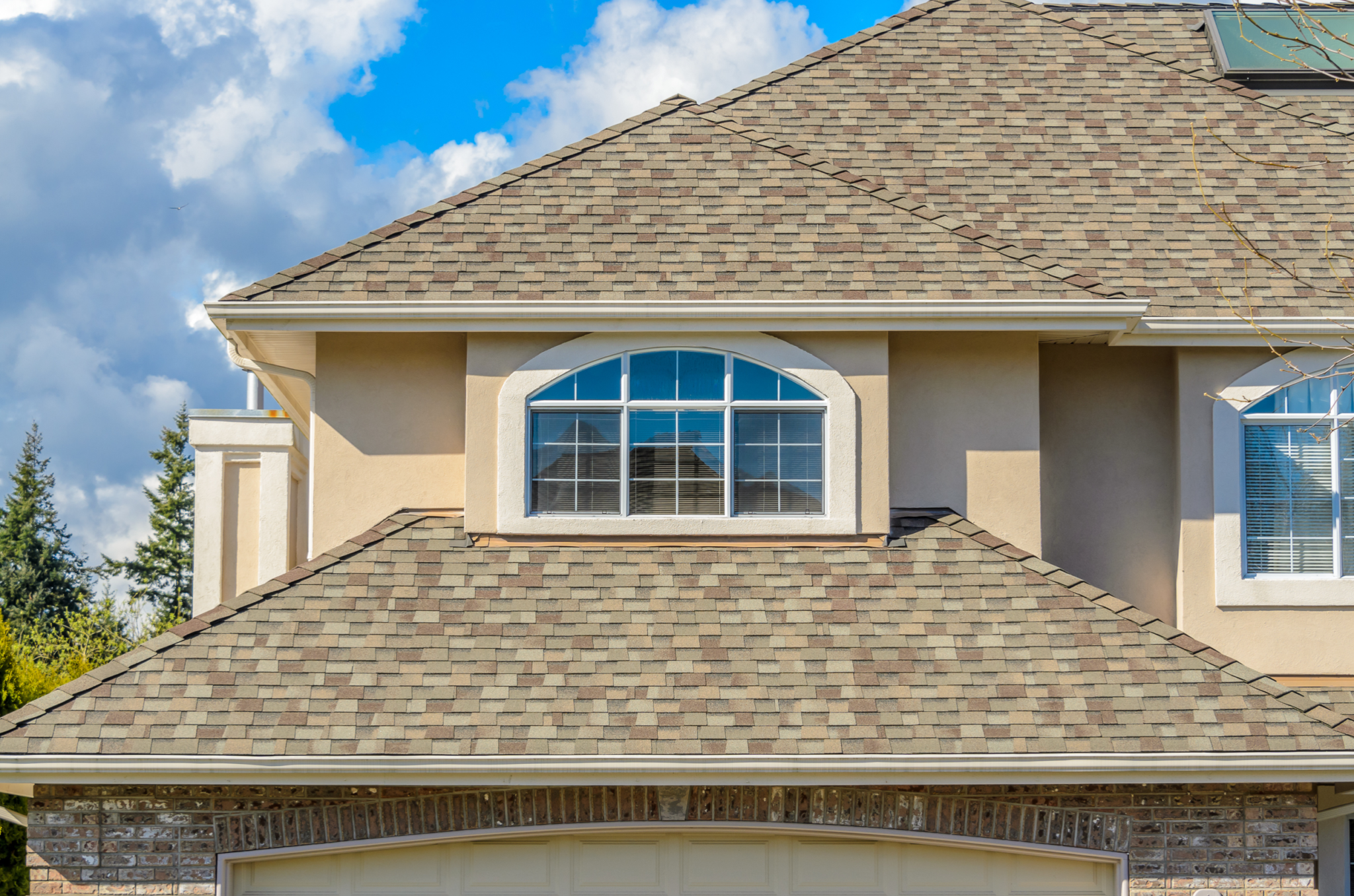 Close-up of house with brown roof, arched dormer, and beige siding